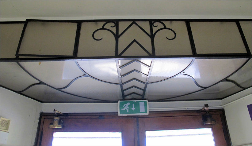 over the inside of the entrance door - opalescent glass in a geometric iron frame  